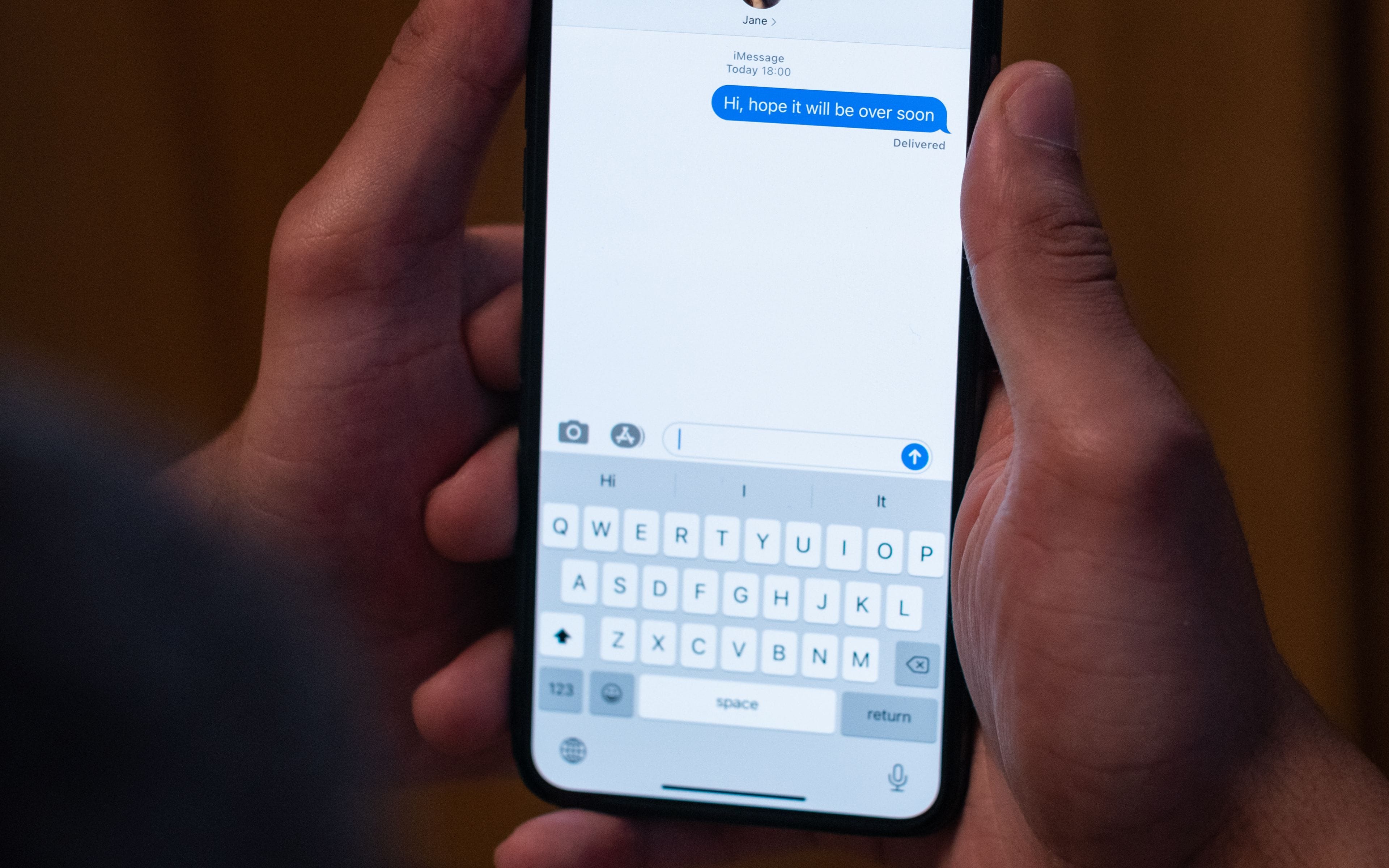 Hands holding a phone with an ongoing chat conversation on screen